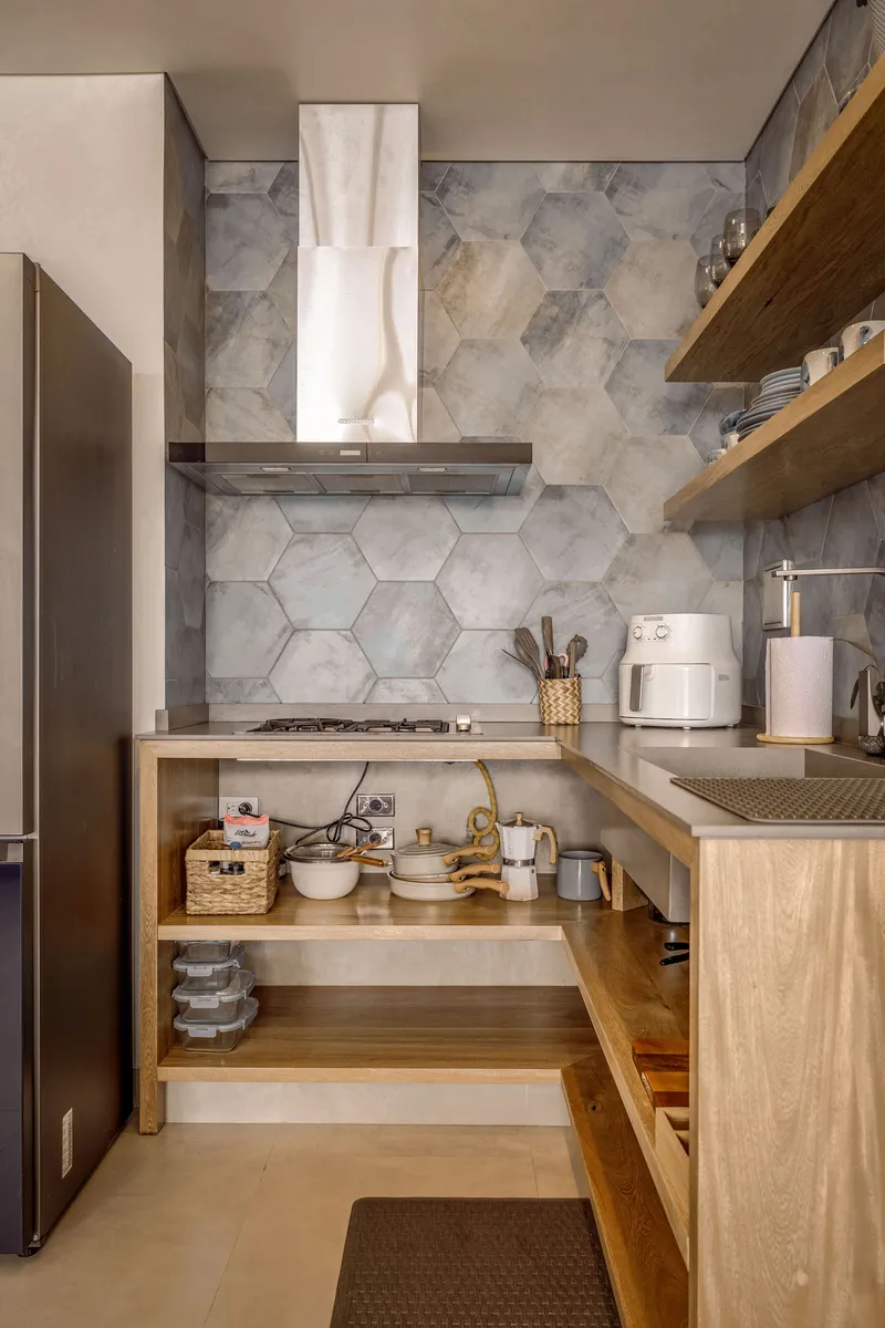 Cocina compacta con azulejo hexagonal gris, encimera de concreto pulido y repisas de madera maciza